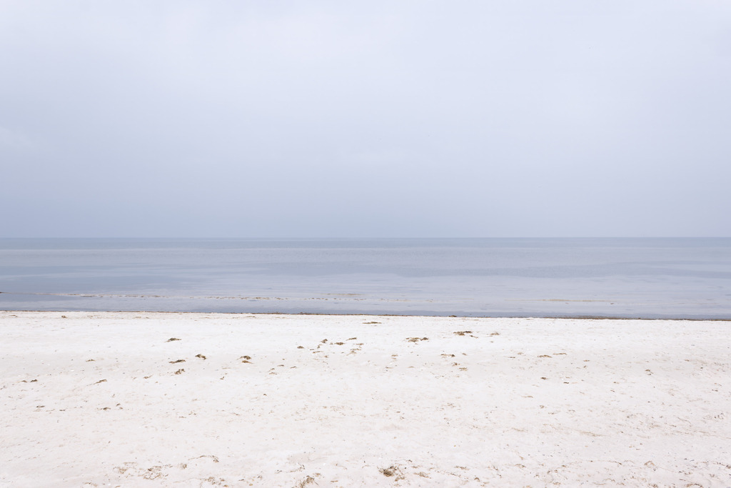 Wandbild: Ostseestille Falshöft - Minimalistischer Küstenblick | Dieses minimalistische Wandbild fängt die pure, meditative Ruhe der Ostseeküste bei Falshöft in einer klaren Komposition ein. Der helle Strand im Vordergrund geht nahtlos in das ruhige Wasser über, während der dezente, neblige Horizont eine zeitlose und friedvolle Atmosphäre ausstrahlt. Die gedeckten, harmonischen Töne machen dieses Kunstwerk zu einer stilvollen Ergänzung für moderne, anspruchsvolle Wohnräume.