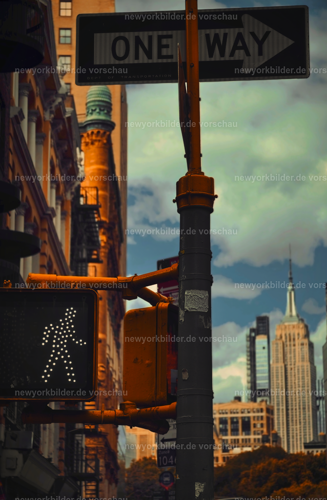 Empire State Building und Straßensymbole – ein Bild voller NYC-Charakter | Dieses Bild vereint alles, was New York so einzigartig macht: Eine Ampel, die grünes Licht für Bewegung gibt, ein markantes One Way Schild, das die Richtung weist, und im Hintergrund das Empire State Building, das majestätisch in den Himmel ragt. Es ist eine Szene voller Symbolik – ein Zusammenspiel aus Ordnung und Freiheit, aus urbaner Struktur und architektonischer Ikone. Die Perspektive lässt den Betrachter spüren, wie die Stadt funktioniert: klare Regeln, endlose Möglichkeiten und eine Energie, die in jedem Detail steckt. Das Empire State Building thront über allem und erinnert daran, warum diese Metropole seit Jahrzehnten Menschen fasziniert. Dieses Motiv erzählt von Dynamik, von der Kraft der Straßen und von der Magie, die entsteht, wenn Licht, Architektur und Bewegung aufeinandertreffen. Ein Bild, das den Charakter New Yorks in seiner reinsten Form einfängt – kraftvoll, lebendig und voller Geschichten.