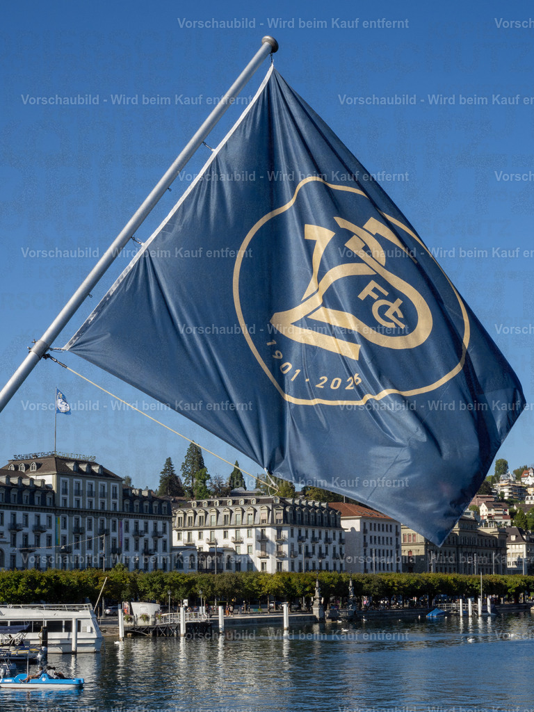 125 Jahre FCL – Luzern in Blau-Weiss | Die blau-weissen Fahnen wehen an der Seebrücke im Wind und zelebrieren das 125-Jahre-Jubiläum des FC Luzern. Dahinter erstreckt sich die Kulisse der Luzerner Seepromenade mit dem traditionsreichen Hotel Schweizerhof. - Realisiert mit Pictrs.com