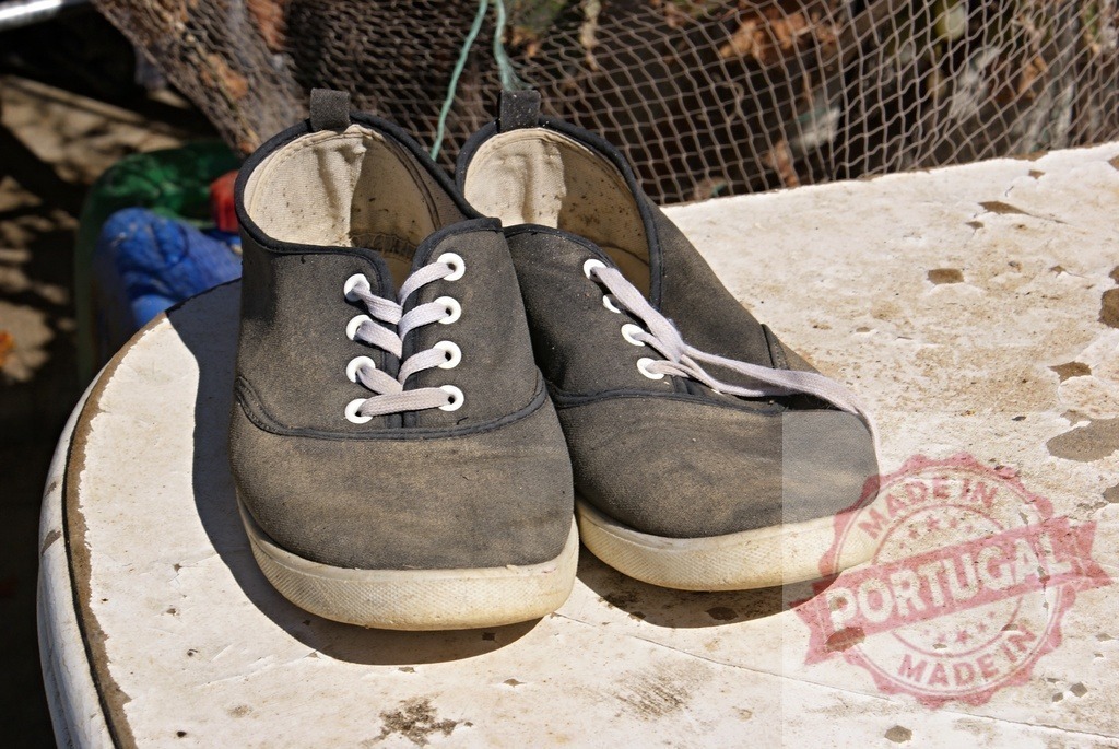 Old dirty canvas shoes resting on a table | Pair of worn canvas shoes sitting on a dirty white table outdoors - Realized with Pictrs.com