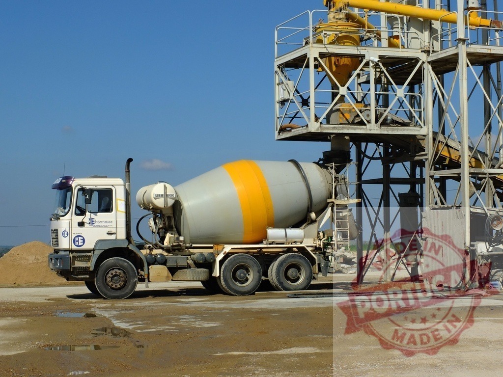 Concrete mixer truck filling at industrial cement plant | Concrete mixer truck loading fresh cement at a construction site facility under a blue sky - Realisiert mit Pictrs.com