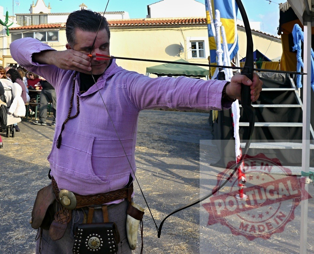 Archer aiming bow and arrow at medieval festival | Man in medieval costume aiming a traditional bow during an outdoor festival event - Realisiert mit Pictrs.com