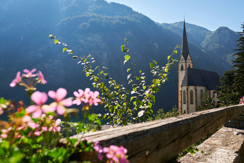 Wallfahrtskirche St. Vinzenz in Heiligenblut | Heiligenblut, Austria - September 15, 2020: Wallfahrtskirche St. Vinzenz in Heiligenblut mit Blumen im Vordergrund. - Realisiert mit Pictrs.com