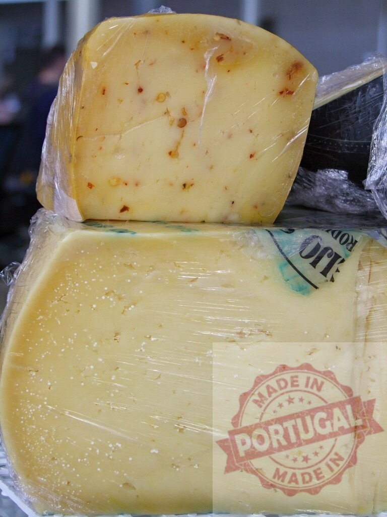 Wrapped artisan pepper jack and aged cheese blocks | Cheese blocks wrapped in plastic film selling at an outdoor market stall - Realized with Pictrs.com