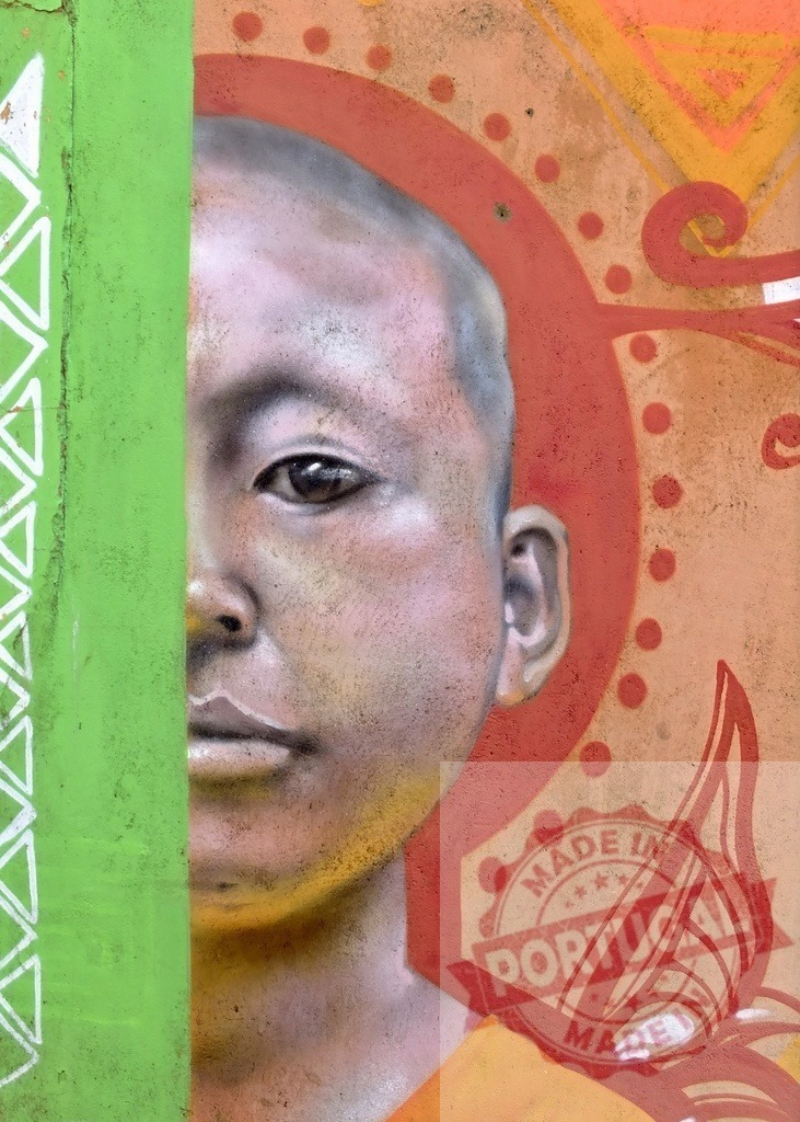 Young monk street art mural on a wall | Close-up of a street art mural depicting a young monk portrait on a wall - Realized with Pictrs.com