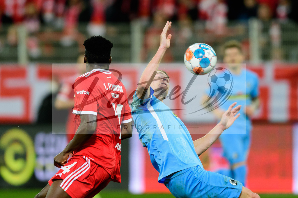 FCUFRE20211215_030 | Fussball, Herren: Taiwo Awoniyi (1. FC Union Berlin) und Philipp Lienhart (SC Freiburg) im Zweikampf bei dem Spiel der 1. Bundesliga zwischen 1. FC Union Berlin und SC Freiburg im Stadion An der Alten Foersterei am 15.12.2021 in Berlin, Deutschland.DFB / DFL REGULATIONS PROHIBIT ANY USE OF PHOTOGRAPHS AS IMAGE SEQUENCES AND/OR QUASI-VIDEO. - Realisiert mit Pictrs.com