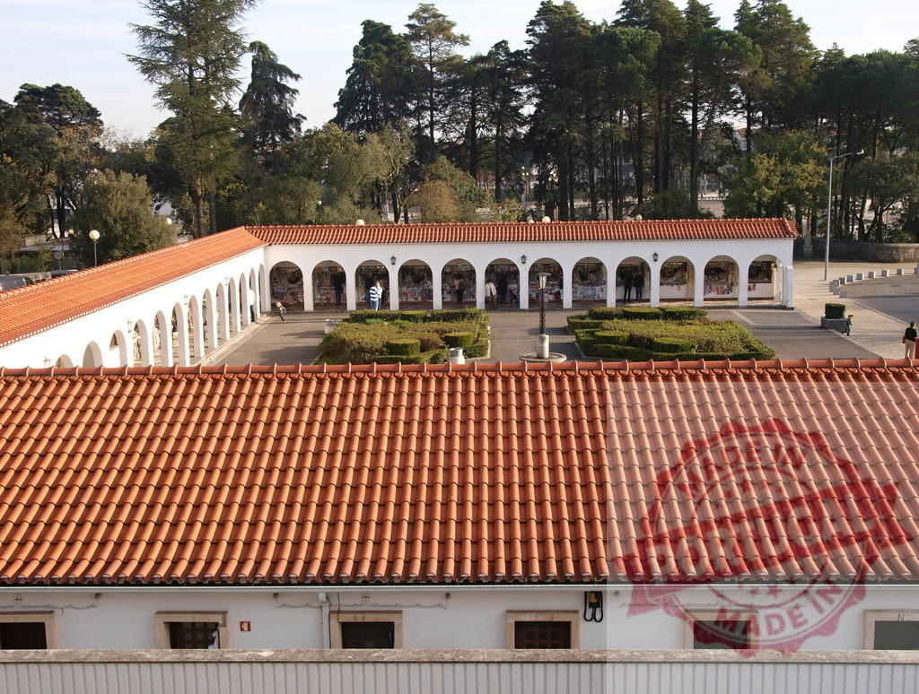 Typical portuguese architecture featuring orange clay roof tiles in Fatima, Portugal | Outdoor view of a traditional portuguese building with orange roof tiles and arches in Fatima, Portugal, a famous pilgrimage site - Realized with Pictrs.com