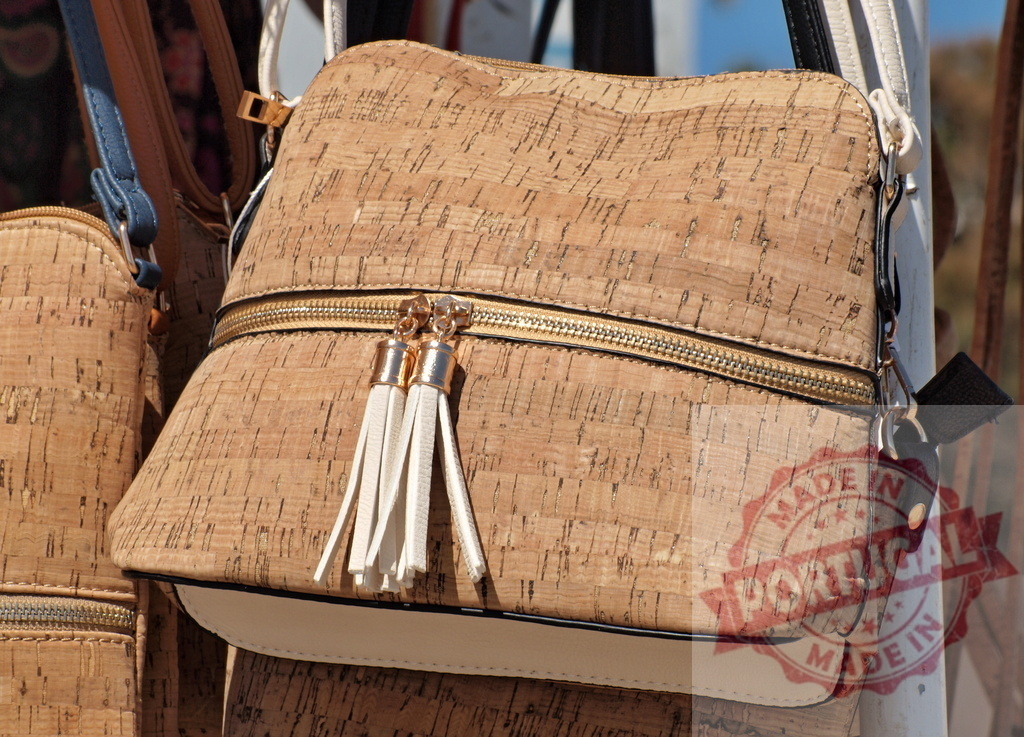 Cork shoulder bag fashion accessory displaying eco-friendly style | Cork shoulder bag with a zipper and decorative tassels hanging on display - Realized with Pictrs.com