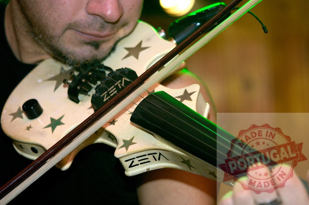 Musician playing electric violin with stars during a concert | Musician playing a white electric violin with stars printed on its body during a concert - Realized with Pictrs.com