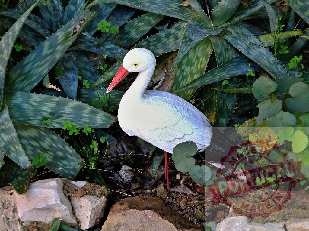 Stork garden ornament standing among aloe plants | Stork figurine decorating a natural outdoor garden with succulents and rocks - Realized with Pictrs.com