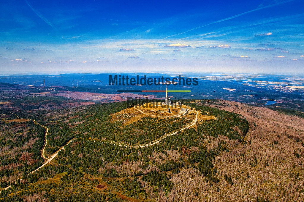 Luftbild_Brocken_8326 | Dieses Luftbild zeigt den Brocken im Nationalpark Harz in Sachsen-Anhalt aus großer Höhe und aus der Perspektive eines Tragschraubers. Die weitläufige Aufnahme vermittelt eindrucksvoll die Dimensionen der Harzlandschaft und zeigt den höchsten Berg Norddeutschlands eingebettet in eine scheinbar endlose Wald- und Mittelgebirgslandschaft.Im Mittelpunkt der Aufnahme liegt das Brockengebiet mit seinen markanten technischen Anlagen und den charakteristischen Gipfelbereichen. Noch beeindruckender wirkt jedoch die Weite der Umgebung. Dichte Wälder, langgezogene Bergrücken, Lichtungen und Täler erstrecken sich bis zum Horizont und verdeutlichen die Größe des Nationalparks Harz. Aus der Luft werden die natürlichen Strukturen der Landschaft besonders deutlich sichtbar.Der klare blaue Himmel und die ausgezeichnete Fernsicht verleihen dem Bild eine außergewöhnliche Tiefe. Die verschiedenen Grüntöne der Wälder, die offenen Flächen und die sanften Höhenzüge des Harzes bilden ein harmonisches Gesamtbild und zeigen Sachsen-Anhalt von seiner landschaftlich schönsten Seite.Dieses Luftbild vermittelt die einzigartige Weite des Harzes und zeigt den Brocken als Wahrzeichen einer der bedeutendsten Naturlandschaften Deutschlands aus einer Perspektive, die nur bei einem Flug mit dem Tragschrauber erlebbar ist. - Realisiert mit Pictrs.com