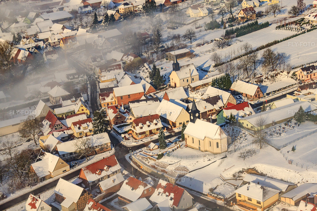 Vue aérienne: Deux églises au centre du village en hiver, recouvertes de neige et de nuages à Wintzenbach dans le département Bas Rhin, France – .Photo: IMG_36197.jpg prise le 02/01/2011 par Werner Riehm/FLY-FOTO.eu – Résolution de l'original: 4752 x 3168 px