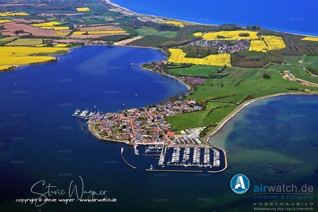 Luftbilder Ostseefjord Schlei, Maasholm, Port Olpenitz, Schleimünde | Die Geschichte Maasholms war lange von der Seefahrt geprägt. 1835 verfügte das Dorf bereits über eine Flotte von 29 Schiffen. Der Bau der künstlichen Schleimündung durch den Olpenitzer Landarm brachte einen Aufschwung, da die Versandung der alten Mündung den Seefahrern zunehmend Probleme bereitete. Der große Schiffsverkehr erforderte sogar einen königlichen Zollkontrolleur in Maasholm. Der Handel mit Kopenhagen war besonders wichtig, wobei Waren oft direkt in den Stadtkanälen vom Schiff verkauft wurden. Der deutsch-dänische Krieg von 1864 unterbrach diese Handelsbeziehungen und führte zum Niedergang der Frachtensegelei.