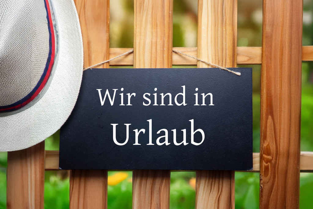 Betriebsferien: Schild mit hinzugefügtem Text WIR SIND IN URLAUB an einem Holzzaun | Betriebsferien: Schild mit hinzugefügtem Text WIR SIND IN URLAUB an einem Holzzaun - Realisiert mit Pictrs.com
