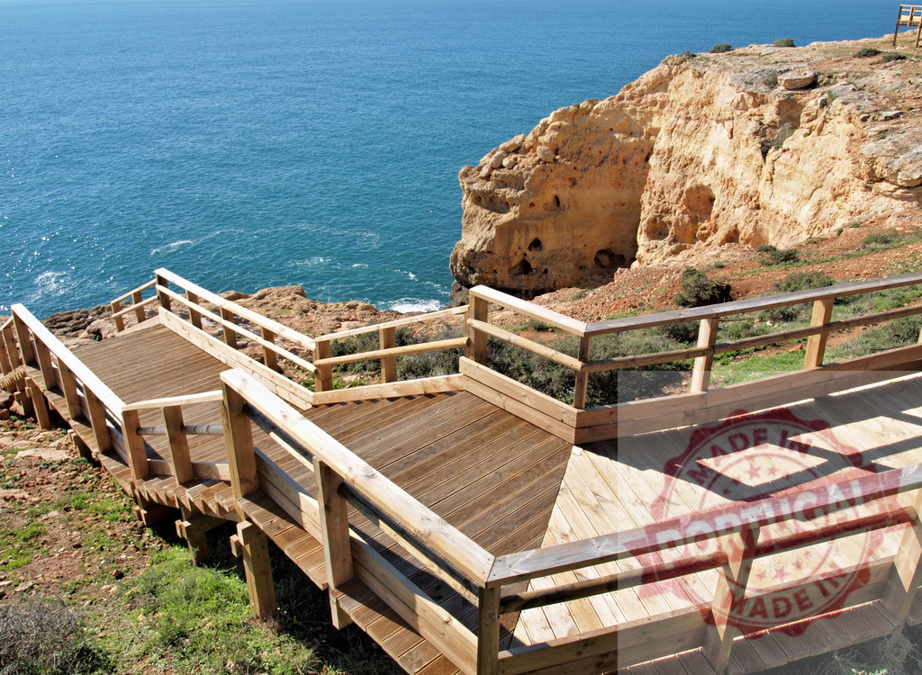Wooden walkway descending a coastal cliff to the ocean | Wooden staircase winding down a rocky cliff towards the blue sea - Realized with Pictrs.com