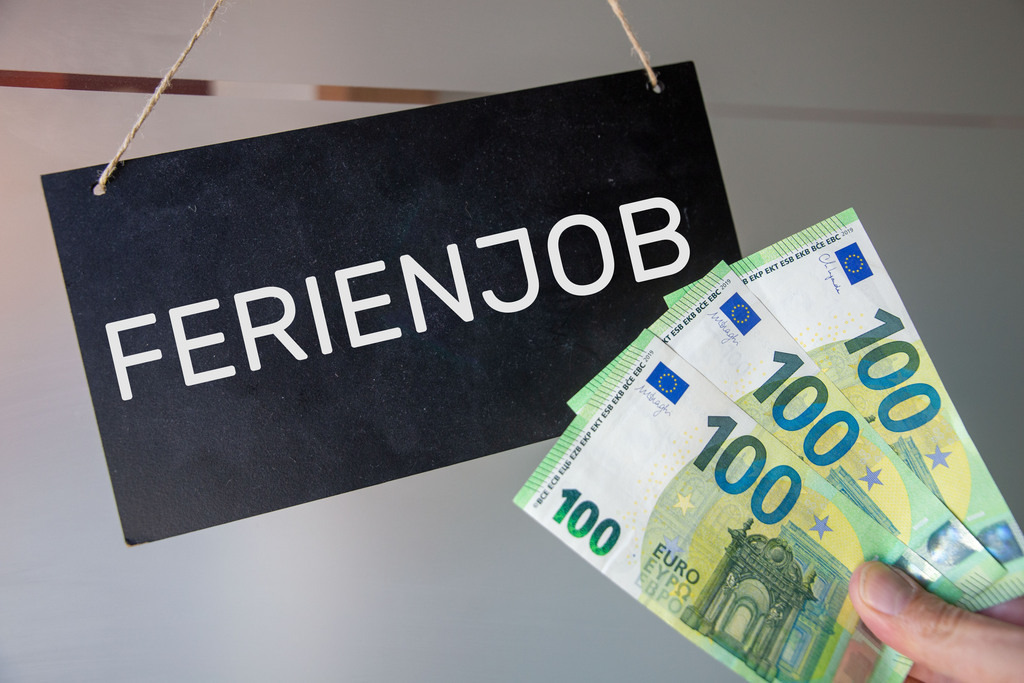 Ferienjob Symbolbild | Ferienjob Symbolbild: Mann hält Eurobanknoten an eine Tafel mit der Aufschrift FERIENJOB - Realisiert mit Pictrs.com