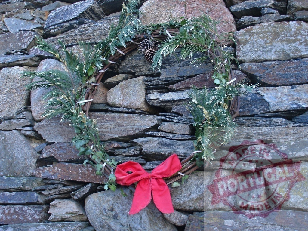 Christmas wreath with red bow hanging on a stone wall | Christmas wreath made of fir branches and pine cone, decorated with a red bow, hanging on a stone wall - Realisiert mit Pictrs.com
