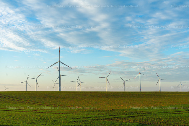 Windräder über grünen Feldern | Weite Feldlandschaft mit mehreren Windkraftanlagen unter einem hellen, strukturierten Himmel. Die klare Horizontlinie, das frische Grün und die moderne Energiegewinnung vermitteln eine ruhige, offene und zeitgemäße Landschaftsstimmung. - Realisiert mit Pictrs.com