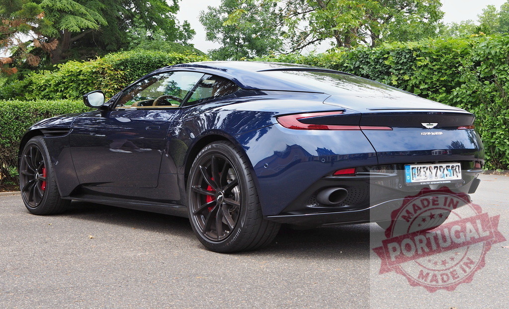 Aston Martin DB11 luxury sports car parked outdoors | Aston Martin DB11 luxury blue sports car parked on a paved road with green trees - Realized with Pictrs.com