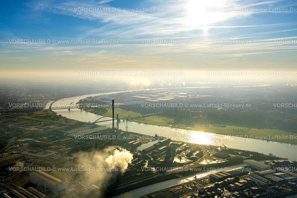 Duisburg241202407 | Luftbild, DK Recycling und Roheisen GmbH Werk, Rheinpark Baugelände mit Hochfelder Eisenbahnbrücke und Brücke der Solidarität über den Fluss Rhein, Rauchwolke im Gegenlicht und blauer Himmel mit Sonne, Hochfeld, Duisburg, Ruhrgebiet, Nordrhein-Westfalen, Deutschland