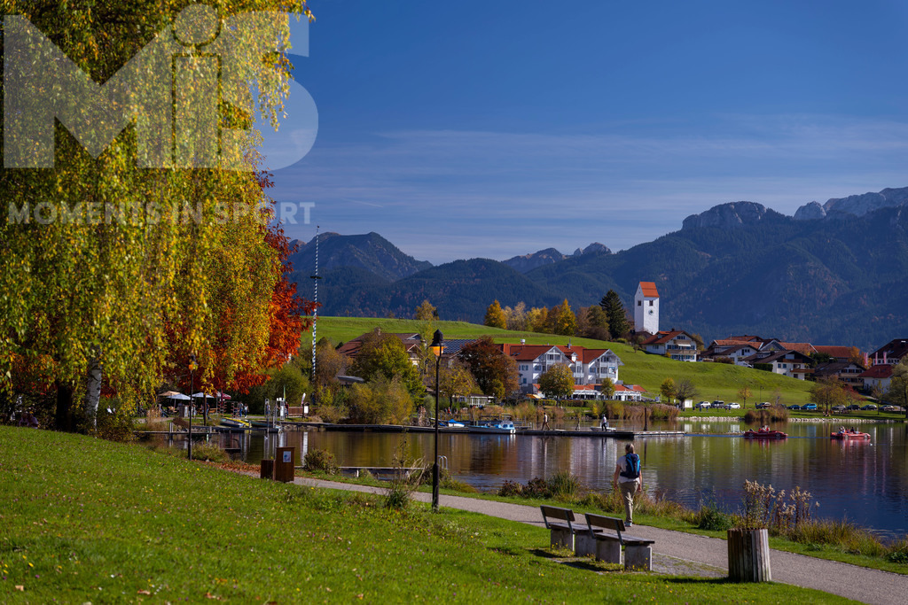 2.Liga-1860-HEIM.jpg | 17.10.2022, Herbst am Hopfensee im Allgäu (Bayern) bei Füssen. Bei sommerlichen Temperaturen geniessen Ausflügler die herbstliche Landschaft am See. Hier die Promenade in Hopfen am See. - Realisiert mit Pictrs.com