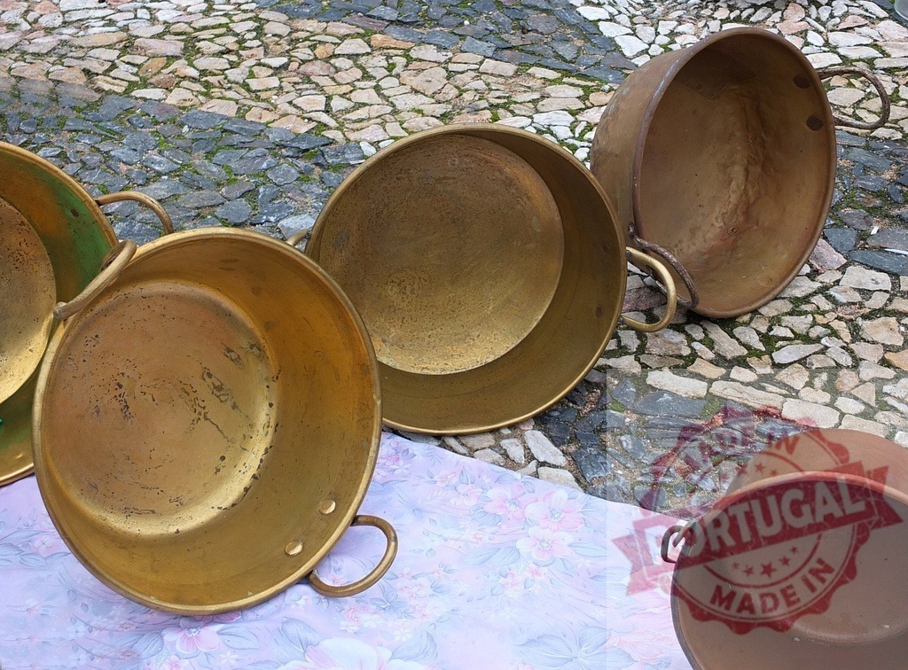 Old brass pots displaying at outdoor market stall | Brass and copper pots sitting on a fabric cover over a cobble street - Realisiert mit Pictrs.com