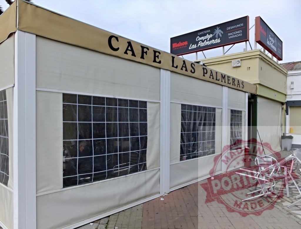 Cafe Las Palmeras outdoor patio restaurant in Spain | Cafe Las Palmeras awning and signage with stacked chairs on an outdoor patio - Realisiert mit Pictrs.com