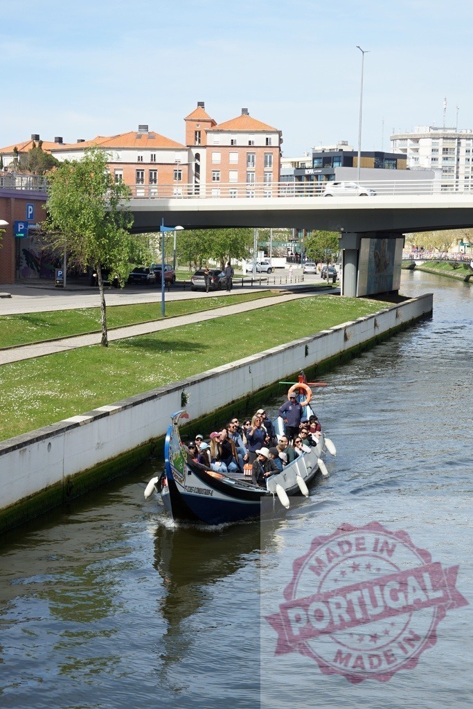 Moliceiro boat carrying tourists on a canal in Aveiro, Portugal. Aveiro - Portugal | Moliceiro boat cruising through a canal in Aveiro, Portugal, carrying many tourists - Realized with Pictrs.com