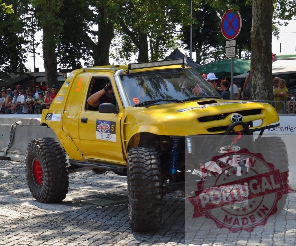 Toyota hilux monster truck driving on cobblestone road | Yellow Toyota Hilux monster truck is driving in front of the public - Realized with Pictrs.com