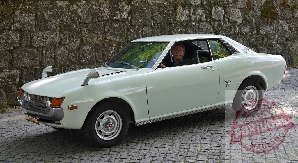 Man driving vintage Toyota Celica on cobblestone road | Man smiling inside classic Toyota Celica coupe on a historic cobblestone street - Realized with Pictrs.com