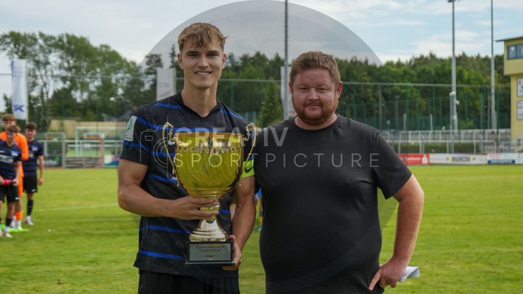 Fußball, Herren, Saison 2025/2026, 3. Luckenwalder Turmpokal, Werner-Seelenbinder-Stadion Luckenwalde, Die Siegerehrung nach Spielende,  | Fußball, Herren, Saison 2025/2026, 3. Luckenwalder Turmpokal, Werner-Seelenbinder-Stadion Luckenwalde, Die Siegerehrung nach Spielende, Im Bild: Marvin Krumhaar (l. Kapitän Hertha BSC U19) erhält von Hendrik Brösel (r. Geschäftsführer Sport) den Luckenwalder Turmpokal - Realisiert mit Pictrs.com