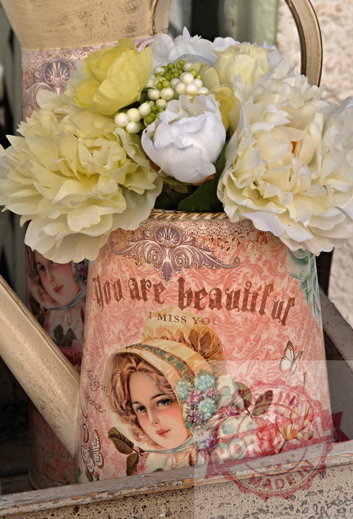 Vintage pink decoupage watering can with artificial flowers | Shabby chic watering can decorated with a woman's portrait and text, holding artificial flowers - Realisiert mit Pictrs.com
