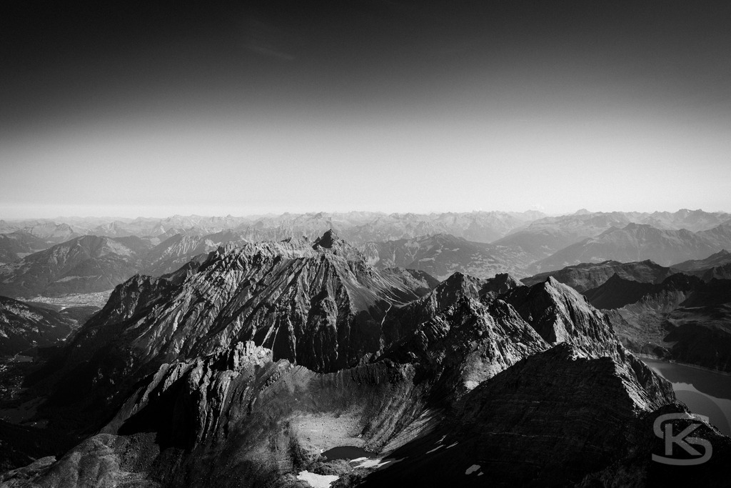 Blick vom Gipfel der Schesaplana - Rätikon Gebirgsmassiv Vorarlberg, Graubünden | Majestätischer Blick von der Schesaplana im Rätikon, Monumentales Schwarzweiß-Foto mit dramatischem Himmel. Der höchste Gipfel des Rätikon-Massivs erhebt sich über schroffe Geröllhänge und beeindruckt mit seiner markanten Felsformation an der Grenze zwischen Vorarlberg und Graubünden. - Realisiert mit Pictrs.com