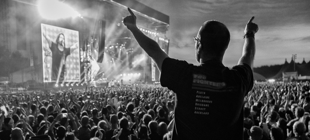 foo-fighters-2018-237 | Besucher beim Konzert der US-amerikanischen Rockband Foo Fighters auf der Trabrennbahn Hamburg-Bahrenfeld am 10. Juni 2018. Auf der Videowand ist der Bandgründer, Gitarrist und Sänger Dave Grohl zu sehen. - Realisiert mit Pictrs.com