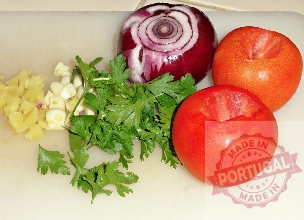 Fresh vegetables preparing for cooking on cutting board | Preparing various fresh vegetables including tomatoes, onion, garlic, and parsley on a cutting board - Realized with Pictrs.com