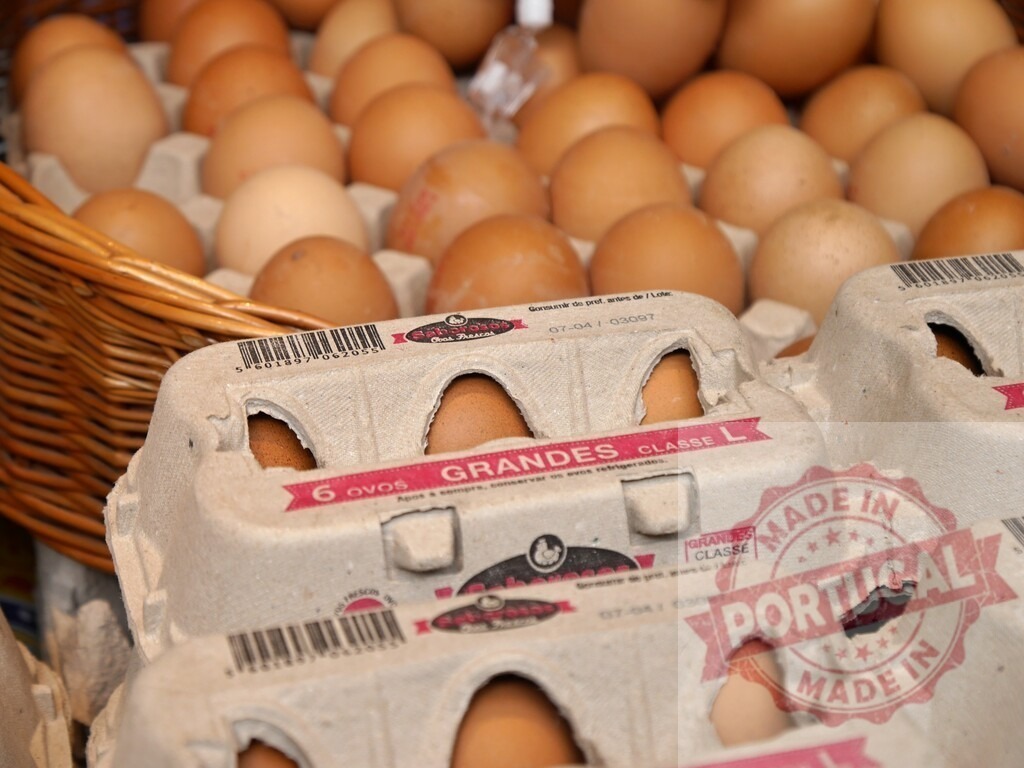 Brown eggs in recyclable cartons at market stall | Eggs in cartons and a basket displaying fresh produce for sale - Realisiert mit Pictrs.com