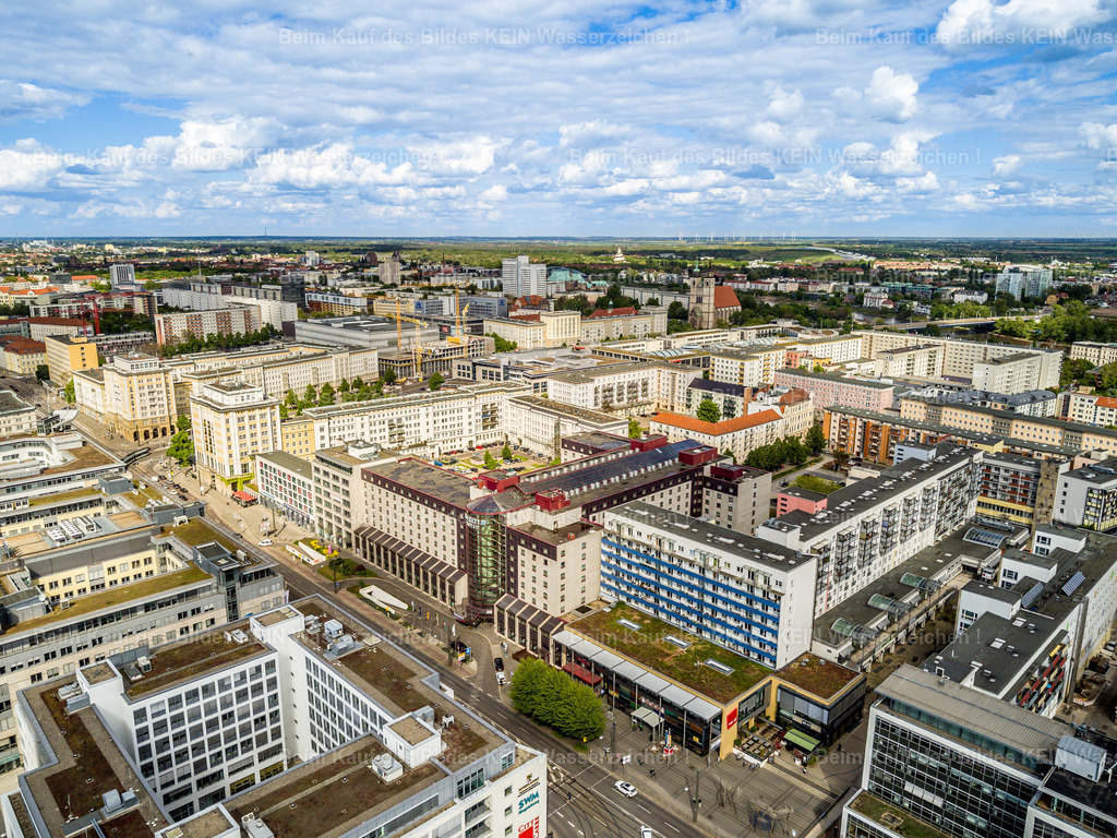 Magdeburg-Maritim-Hotel_Leiterstraße_Otto_verdi-0010 | Die Luftaufnahme zeigt einen weitläufigen Ausschnitt der Magdeburger Innenstadt aus großer Höhe. Im Vordergrund und im Zentrum des Bildes liegen dicht bebaute Wohn- und Geschäftsquartiere mit unterschiedlichen Gebäudetypen, begrünten Dachflächen und Innenhöfen. Die Leiterstraße, die Otto-von-Guericke-Straße und die Ernst-Reuter-Allee gehören zu den wichtigen innerstädtischen Verkehrsachsen in diesem Bereich. Das Maritim Hotel setzt mit seiner markanten Architektur einen weiteren Orientierungspunkt im Stadtbild. –  – Die Magdeburger Innenstadt ist durch verschiedene Phasen der Stadtentwicklung geprägt. Nach den schweren Zerstörungen des Zweiten Weltkriegs wurden große Teile des Zentrums neu aufgebaut und später durch weitere Wohn-, Büro- und Geschäftsbauten ergänzt. Dadurch stehen heute unterschiedliche Baustile und Gebäudeformen nebeneinander. Breite Straßen, größere Gebäudekomplexe und begrünte Innenhöfe prägen das Erscheinungsbild vieler Quartiere. –  – Aus der Vogelperspektive wird die Struktur der Innenstadt besonders deutlich. Straßen verbinden die einzelnen Bereiche miteinander, während geschlossene Häuserblöcke und größere Gebäudekomplexe die Stadtlandschaft gliedern. Die Aufnahme zeigt Magdeburg nicht als Sammlung einzelner Sehenswürdigkeiten, sondern als zusammenhängenden Stadtraum mit seinen Wohngebieten, Geschäftsbereichen und Verkehrsachsen. –  – Das Luftbild vermittelt einen Überblick über die Magdeburger City und ihre bauliche Vielfalt. Es hält fest, wie sich historische Spuren, Nachkriegsarchitektur und moderne Stadtentwicklung zu dem heutigen Erscheinungsbild der Landeshauptstadt verbinden. - Realisiert mit Pictrs.com