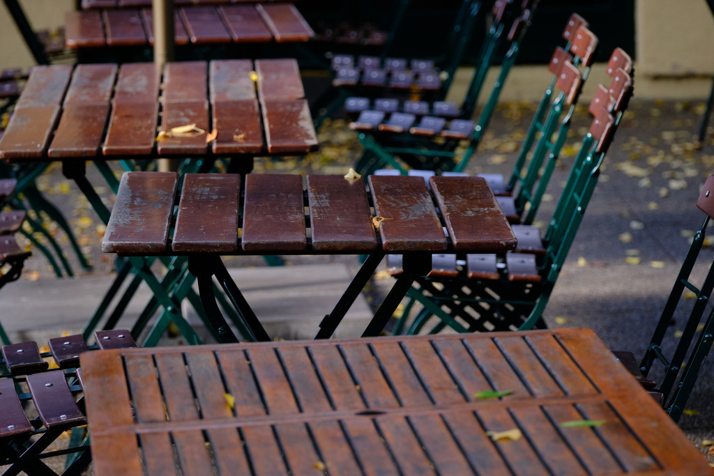 Impressionen aus dem Pratergelände | Wien, Austria - September 29, 2025: Impressionen aus dem Pratergelände, lehre Holzstühle und Holztische einer Gastwirtschaft. - Realisiert mit Pictrs.com