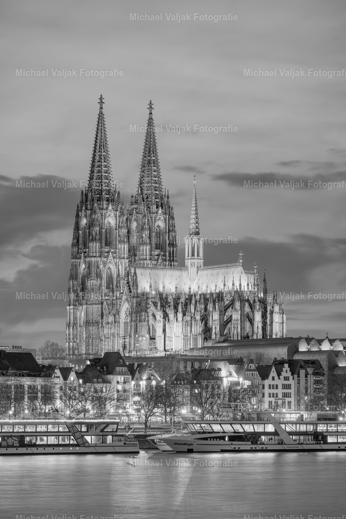 Kölner Dom am Abend mit neuer LED-Beleuchtung schwarz-weiß | Die Schwarz-weiß Aufnahme des Kölner Doms am Abend offenbart die majestätische Architektur, die durch die neue LED-Beleuchtung hervorgehoben wird. Die Beleuchtung akzentuiert die gotischen Elemente und verleiht dem historischen Monument eine moderne Note. - Realisiert mit Pictrs.com
