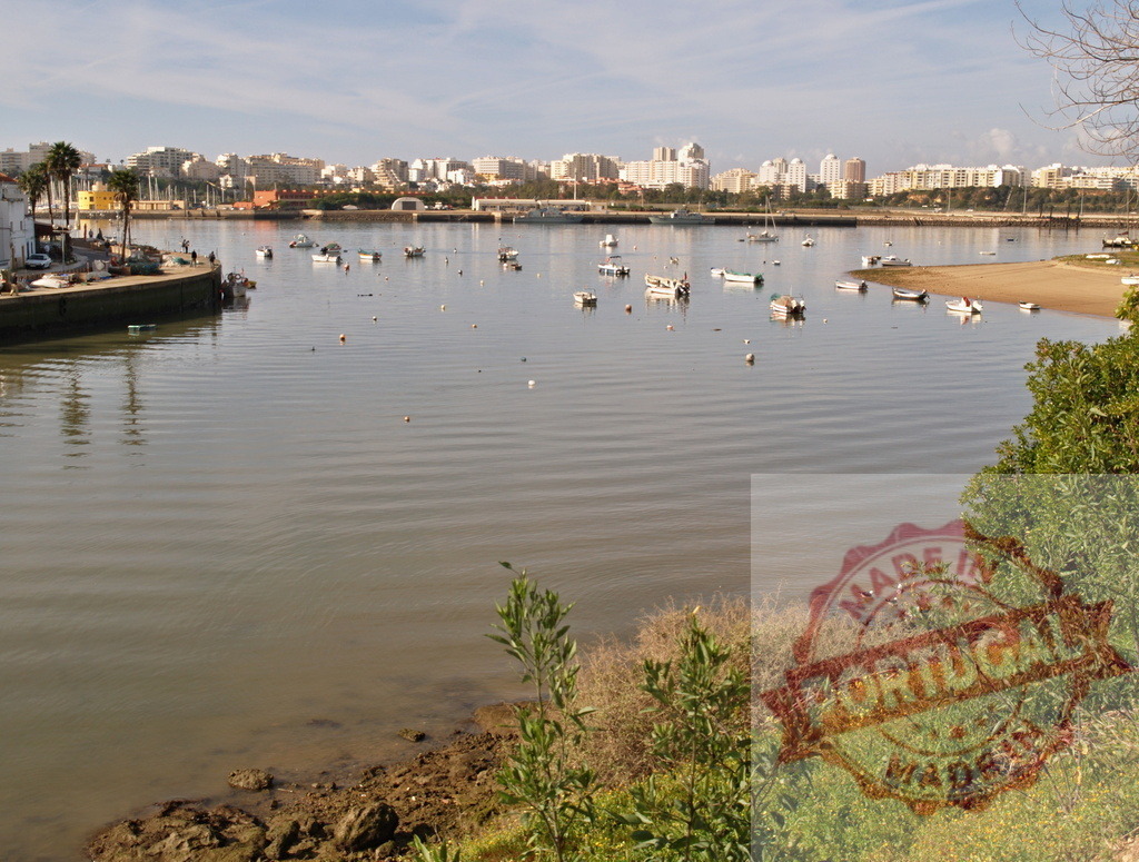 Portimão cityscape reflecting on Arade river with boats | Portimão cityscape with boats moored on the calm waters of the Arade River, Algarve - Realized with Pictrs.com