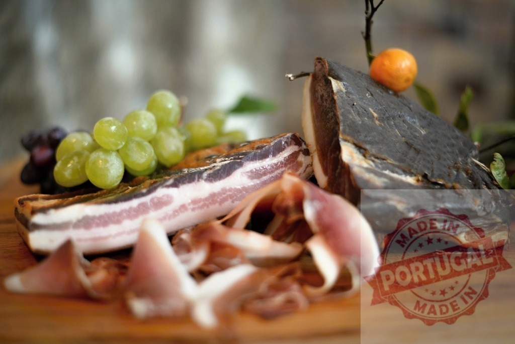 Cured meat platter offering prosciutto grapes and citrus | Cured meats, prosciutto, bacon, grapes, and citrus on a wooden board creating a gourmet appetizer - Realized with Pictrs.com