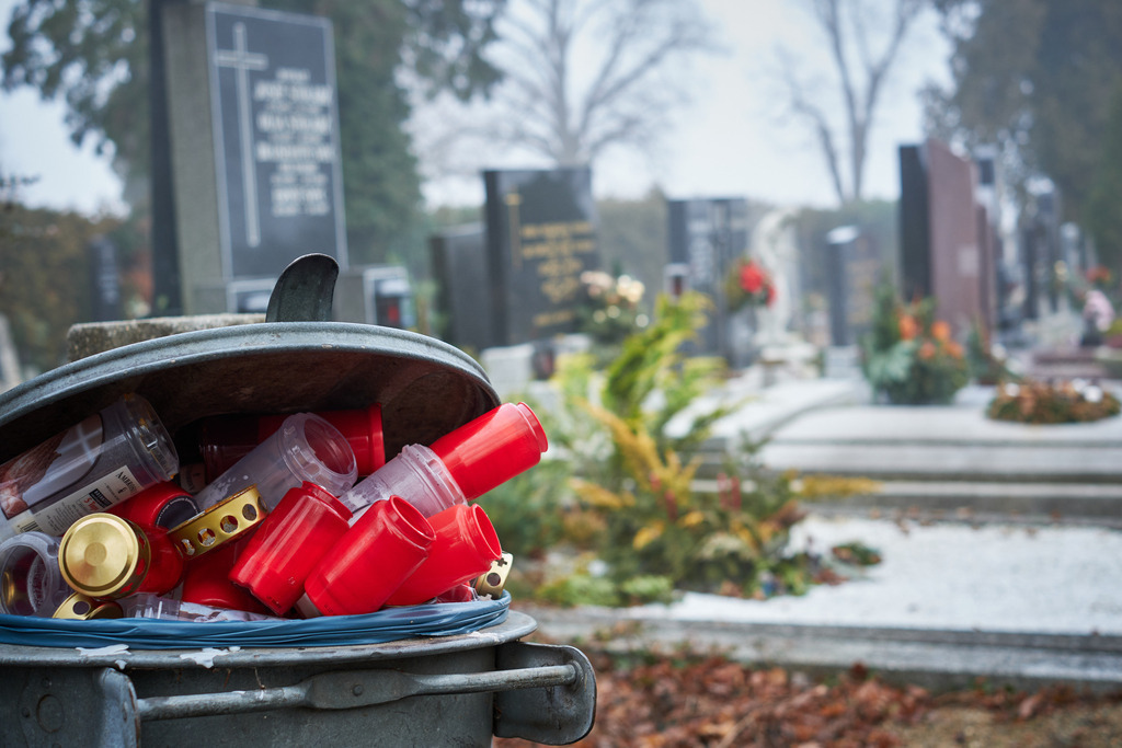 Leere Kerzenhalter in der Mülltonne beim Friedhof | Austria - January 02, 2022: Leere rote Kerzenhalter in einer Mülltonne beim Friedhof. - Realisiert mit Pictrs.com