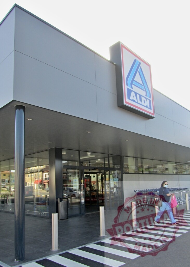 People shopping arriving at Aldi supermarket entrance | Woman in face mask walking towards the entrance of an Aldi grocery store - Realisiert mit Pictrs.com