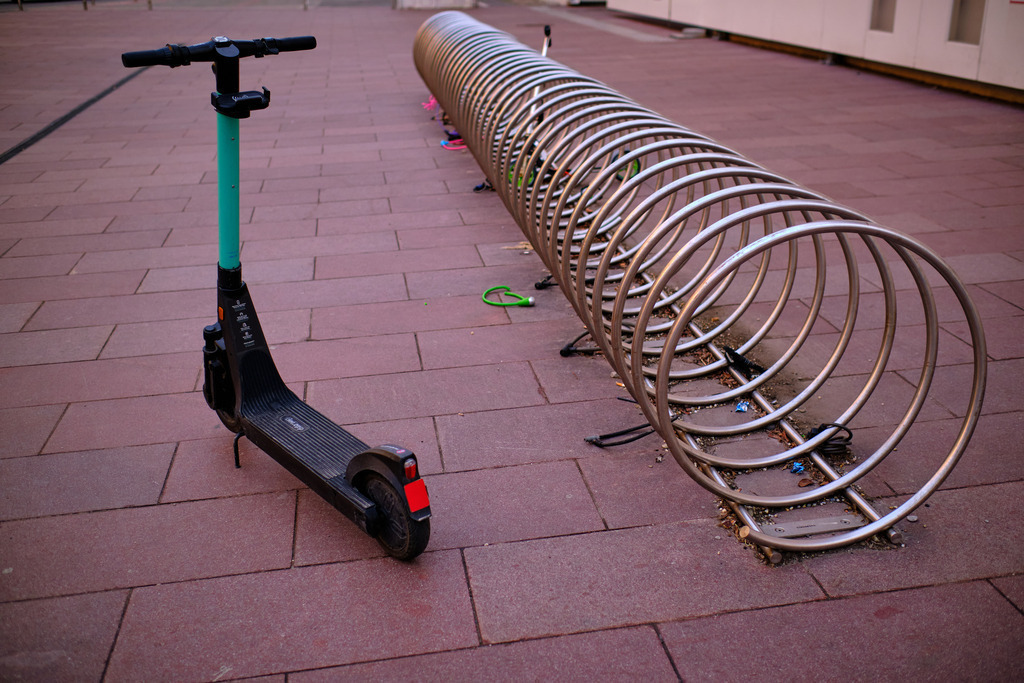 abgestellter E-Roller vor einem Fahrradständer | Wien, Austria - March 13, 2021: abgestellter E-Roller  vor einem Fahrradständer in einer Wohnanlage. - Realisiert mit Pictrs.com