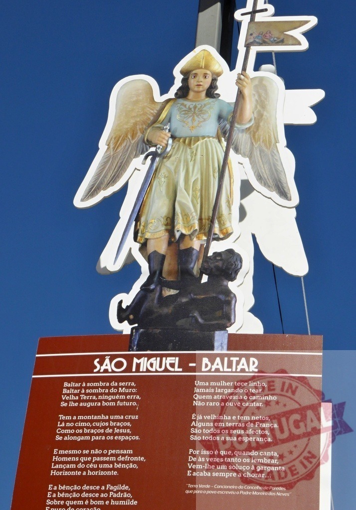 Archangel Michael statue defeating dragon on religious sign | Archangel Michael statue with sword and flag standing on a defeated dragon, next to a Portuguese poem - Realisiert mit Pictrs.com