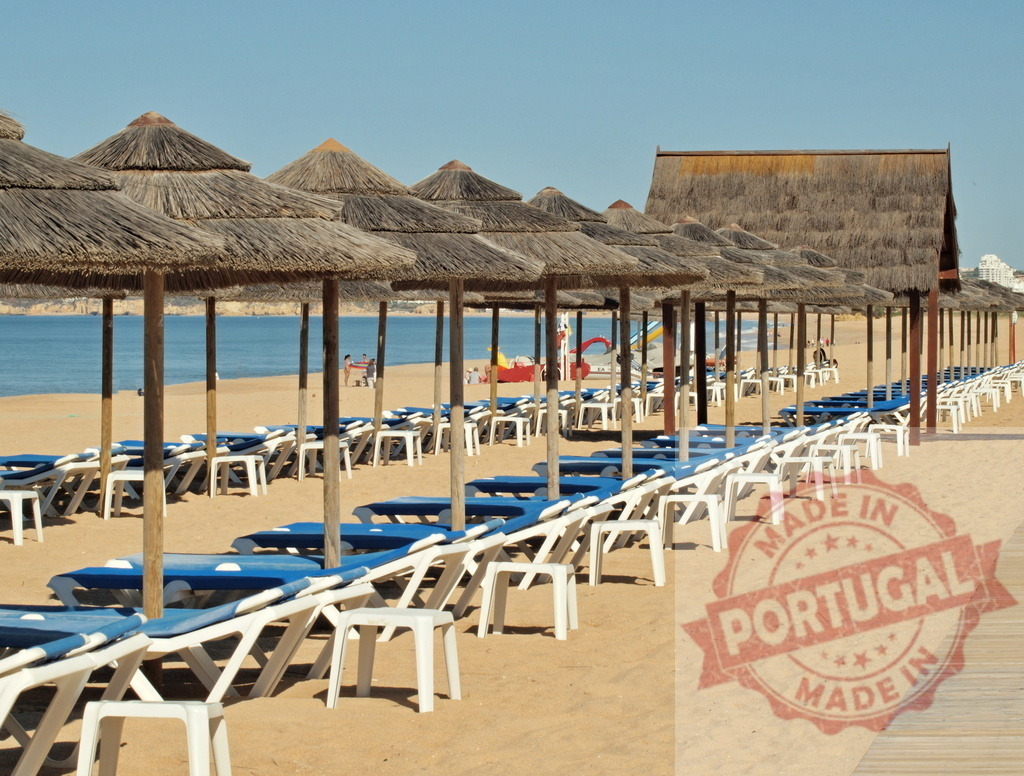 Algarve beach with rows of straw umbrellas and sunbeds | Rows of straw umbrellas and sunbeds on a sandy Algarve beach overlooking the ocean - Realisiert mit Pictrs.com