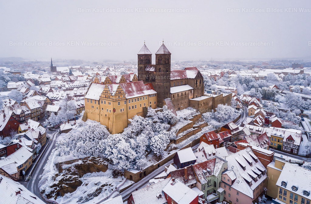 Schloss Quedlinburg UNESCO Harz Herbst-0014_aus_Flux_upscale_LU | Das Foto ist eine Luftaufnahme aus ca. 50m Höhe. Es zeigt das Schloss Quedlinburg, ein UNESCO Weltkulturerbe im Harz im Sommer. Das Schloss ist umgeben von Fachwerkhäusern mit roten Ziegeln und einigen grünen Laubbäumen.Verwandle das Foto in einen romantische Winterlandschaft. Füge etwas Schnee hinzu, Pulverschnee auf den Bäumen und Dächern der Häuser, nicht zu 100%. Bedecke die Bäume, die Landschaft, die Hausdächer mit Schnee. Ansonsten lasse alles unverändert. Ändere keine Textur. Belasse alle Details der Gebäude, belasse die Landschaft so, wie sie sind. Füge Sie nichts anders hinzu. Der Himmel bleibt ebenfalls original. - Realisiert mit Pictrs.com