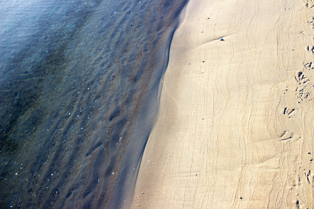 Wandbild: Ruhiges Wasser am Strand in Damp | Dieses Wandbild im Querformat zeigt den Strand und das Meer in Nahaufnahme. Auf der Ostsee befinden sich nur sehr kleine Wellen. Im Vordergrund befindet sich der helle Strand.  - Realisiert mit Pictrs.com