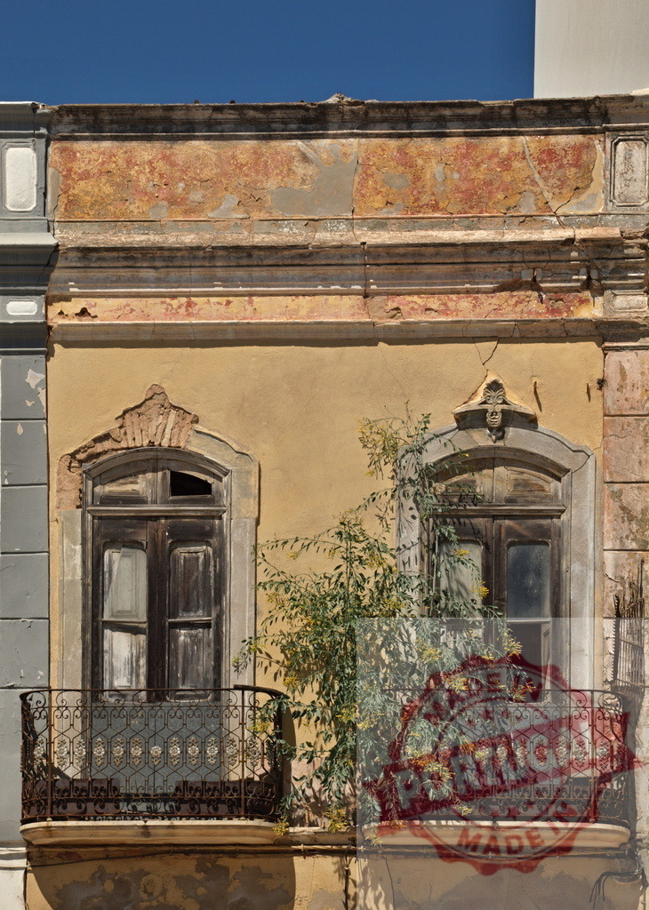 Old building facade showing weathered windows and overgrown balcony | Old building facade with peeling paint, weathered windows, and vegetation growing on a balcony - Realized with Pictrs.com