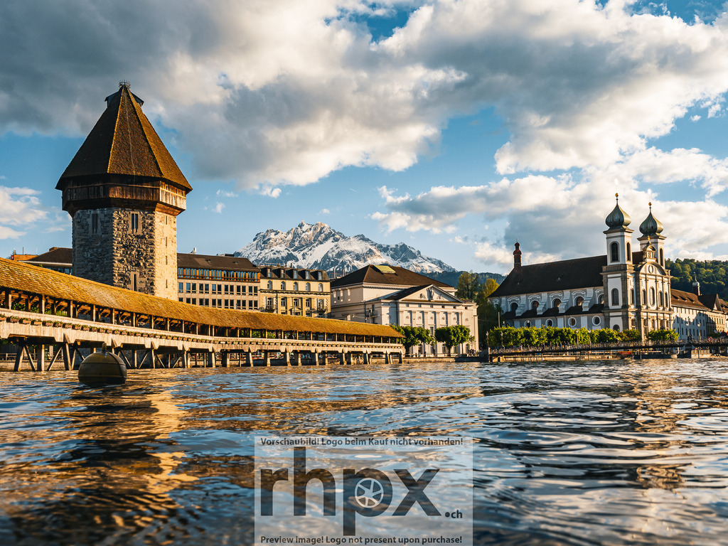 Kapellbrücke und Wasserturm Luzern im Abendlicht | Die tief stehende Sonne bricht sternförmig hinter dem Wasserturm hervor und taucht die Kapellbrücke sowie die Altstadt von Luzern in warmes Abendlicht.  - Realisiert mit Pictrs.com